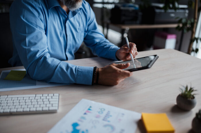 Man is seated desk building using tablet computer desk is adorned with office
