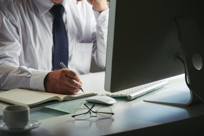 Mid section unrecognizable man formalwear making notes workplace computer
